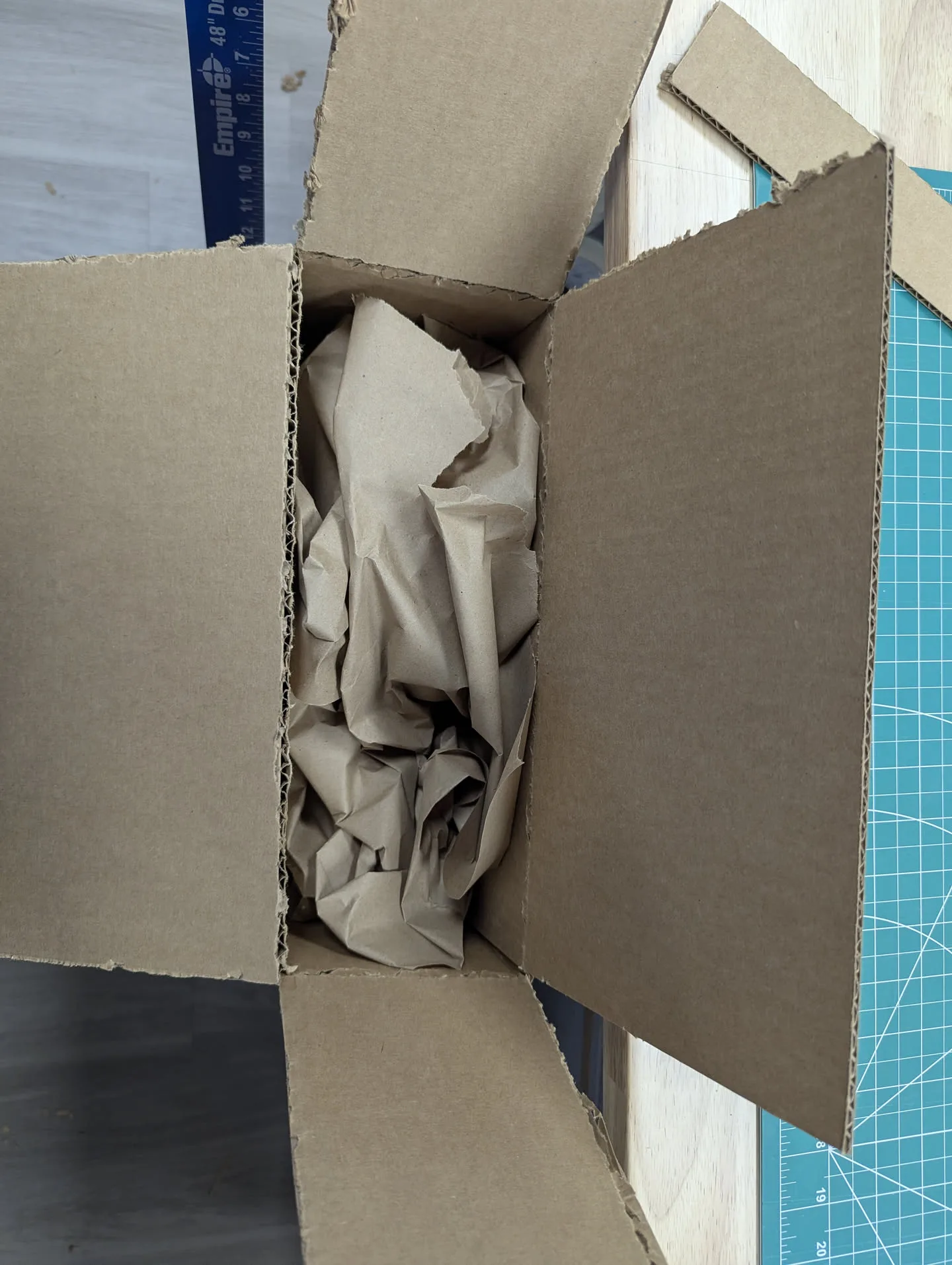A cardboard box packed with crumpled kraft paper on the packing bench at Mailbox Plus