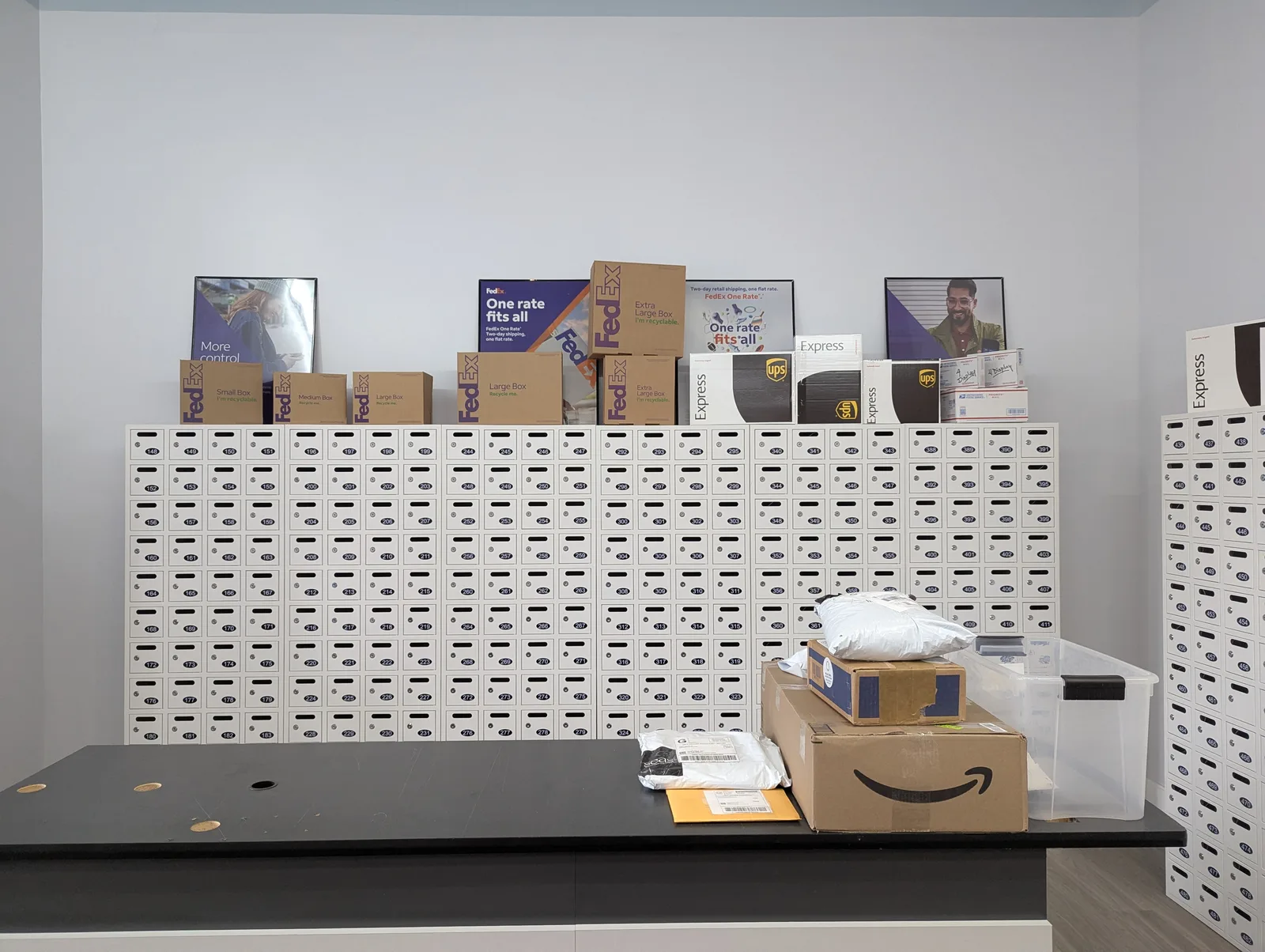 Shipping counter at Mailbox Plus with multiple carriers' shipments staged for pickup