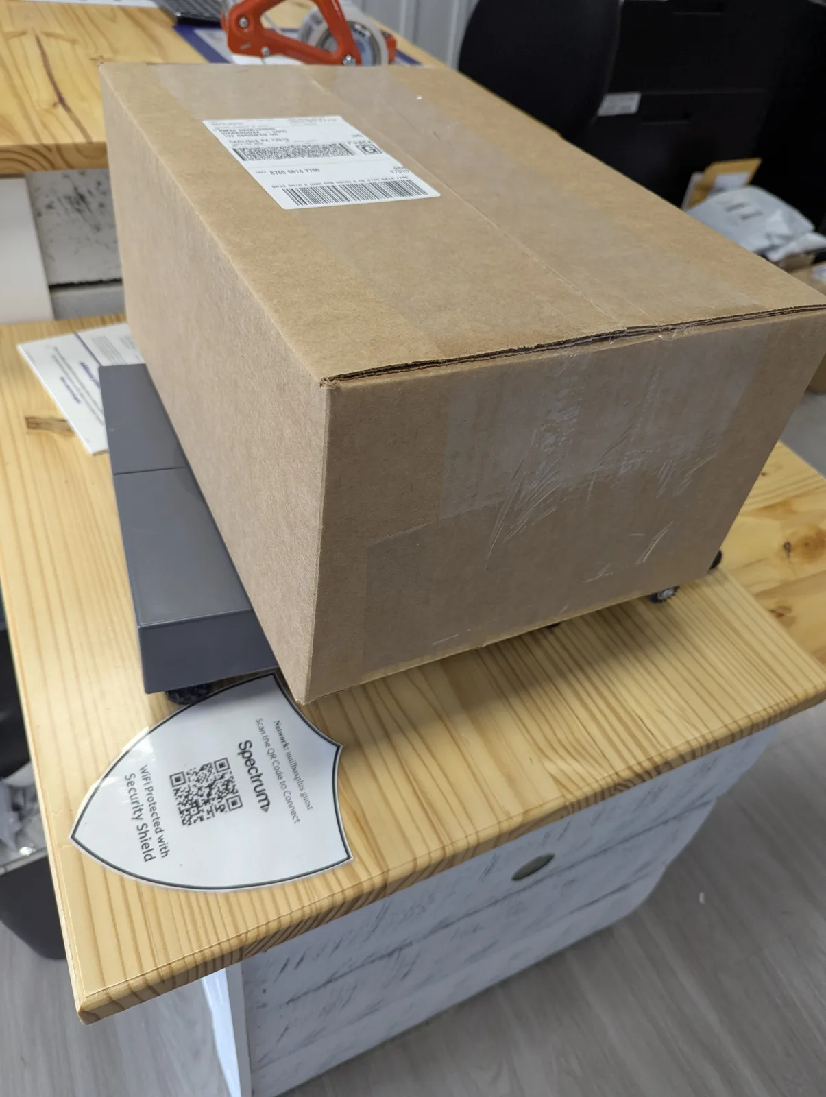 A sealed cardboard box on the parcel scale at the Mailbox Plus counter in Concord Township, where every carrier's surcharge stack gets quoted before it ships.
